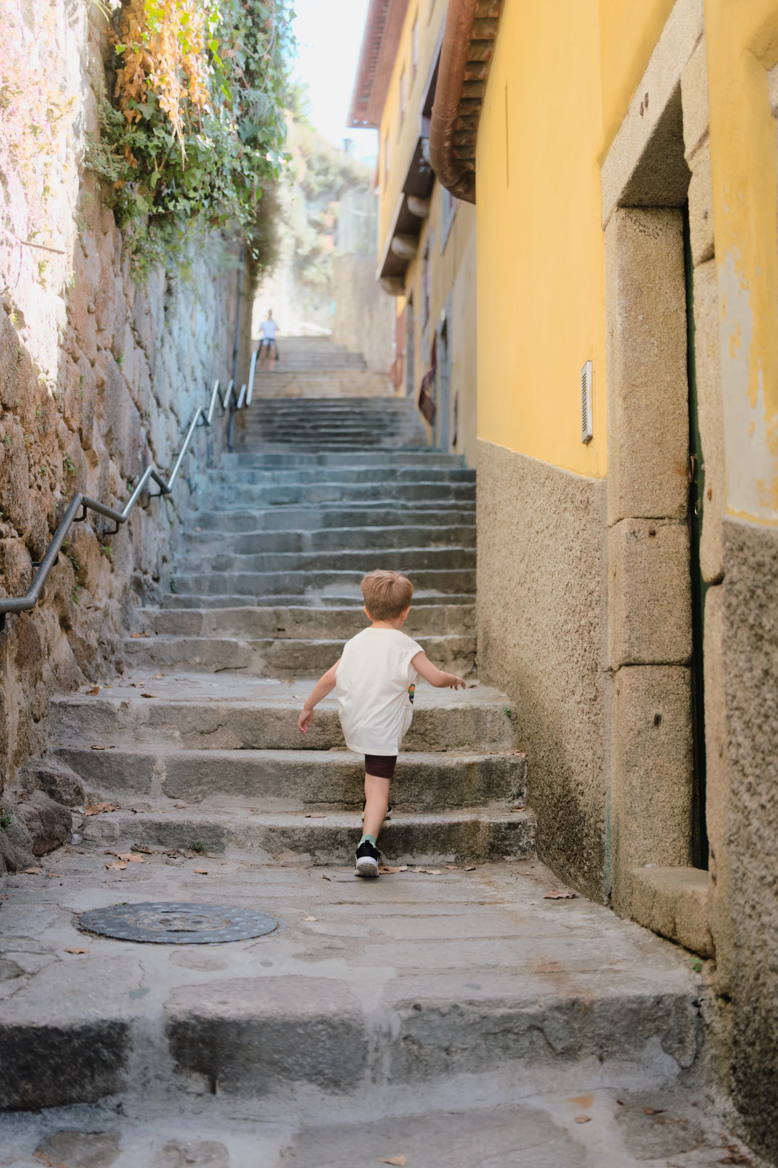 A small figure seen from behind walking up a narrow stone street